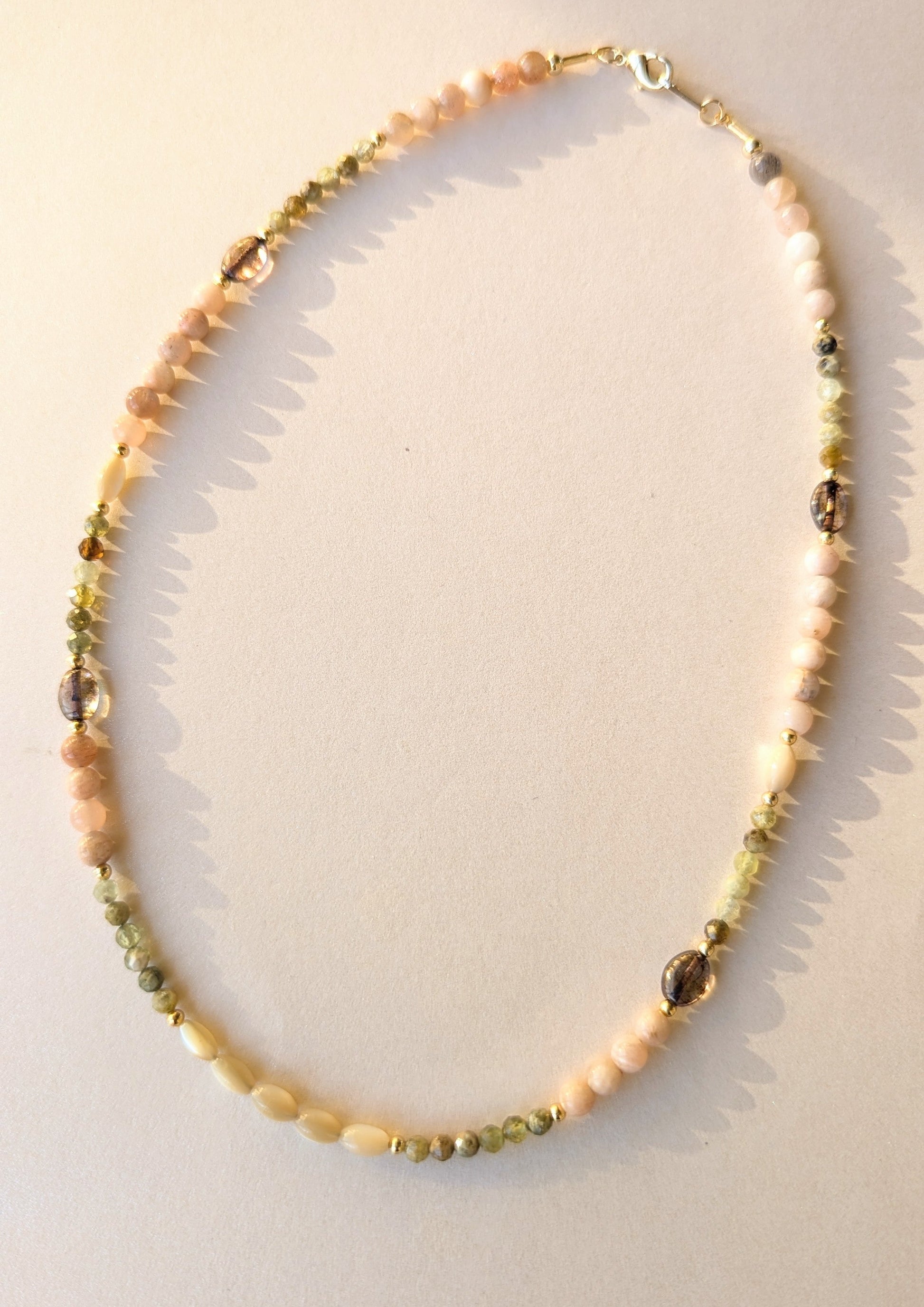 Necklace with multicolored gemstone beads on a light background.