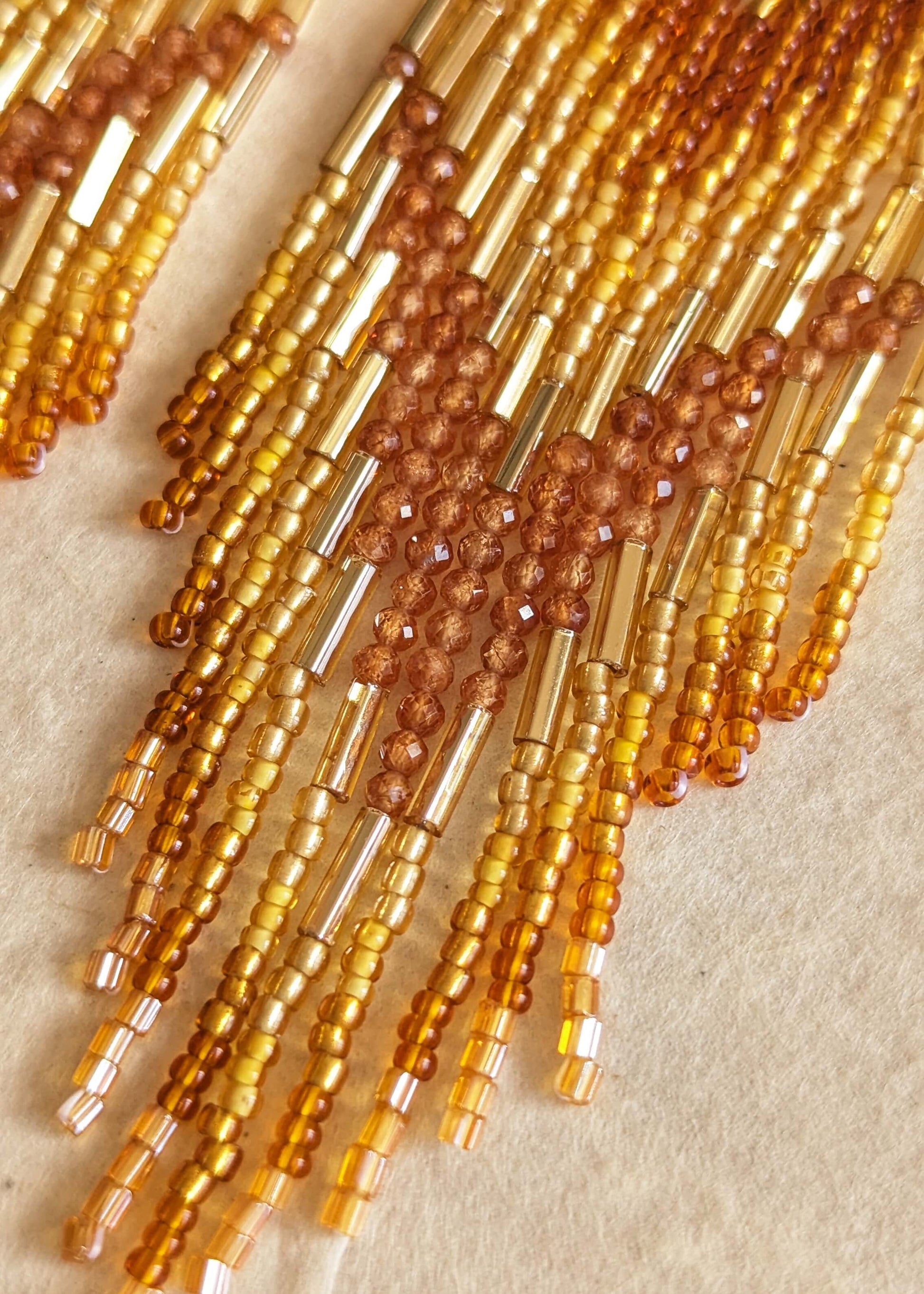 Close-up of amber-colored beaded strands on a beige background.