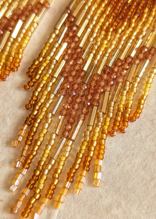 Close-up of amber-colored beaded strands on a beige background.
