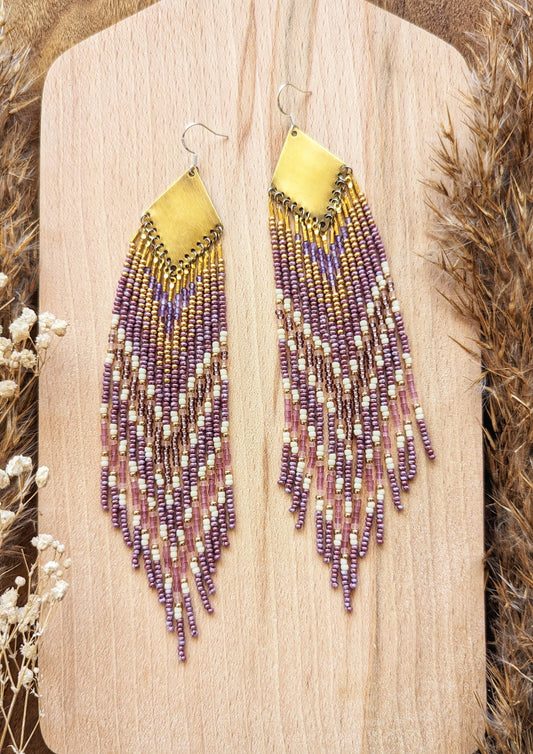 Moon & Milk long beaded earrings in gold, lavender, and cream tones, handcrafted with glass beads and brass for a soft, radiant native-inspired fringe design.