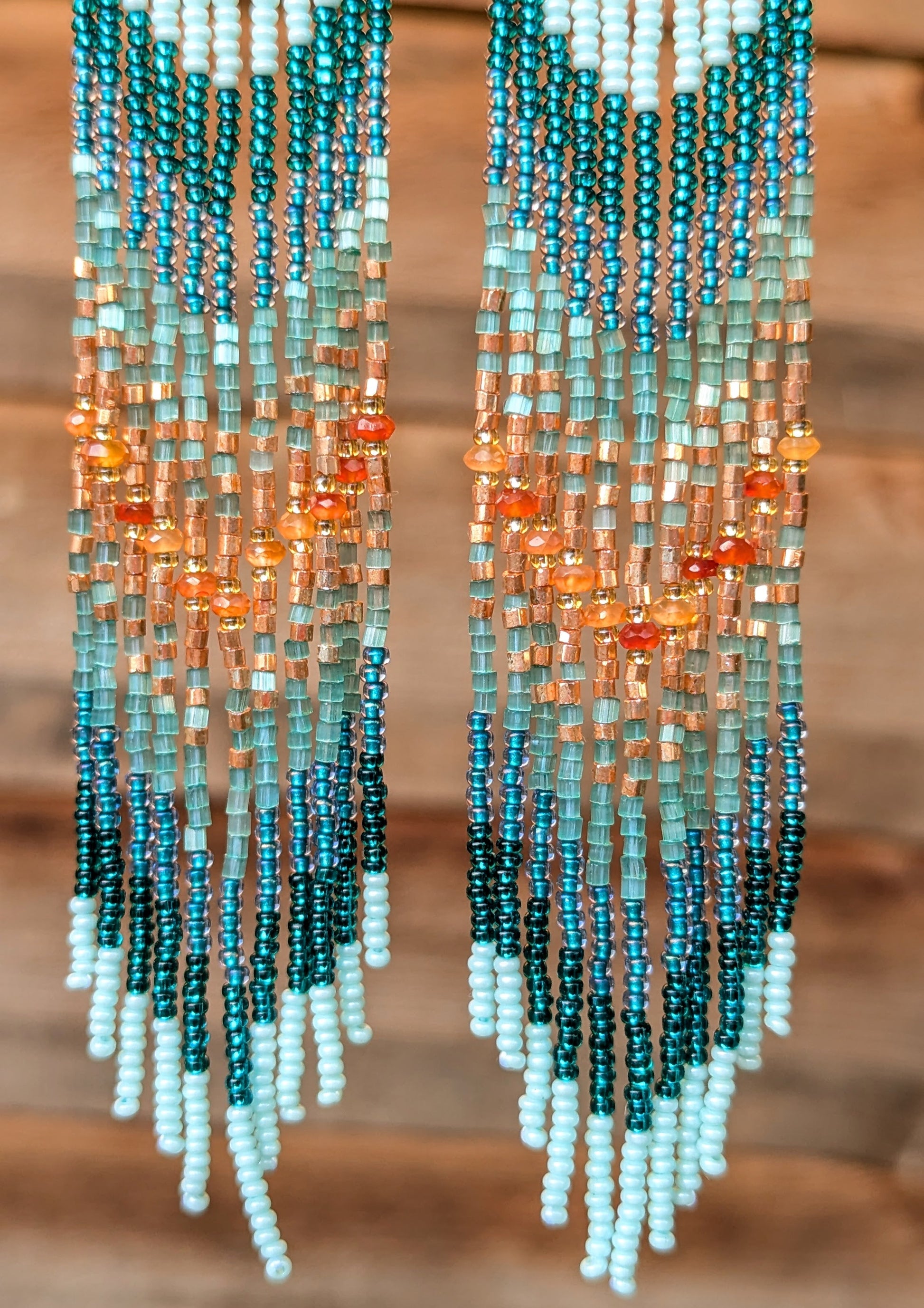 Beaded earrings with a gradient of colors on a wooden background