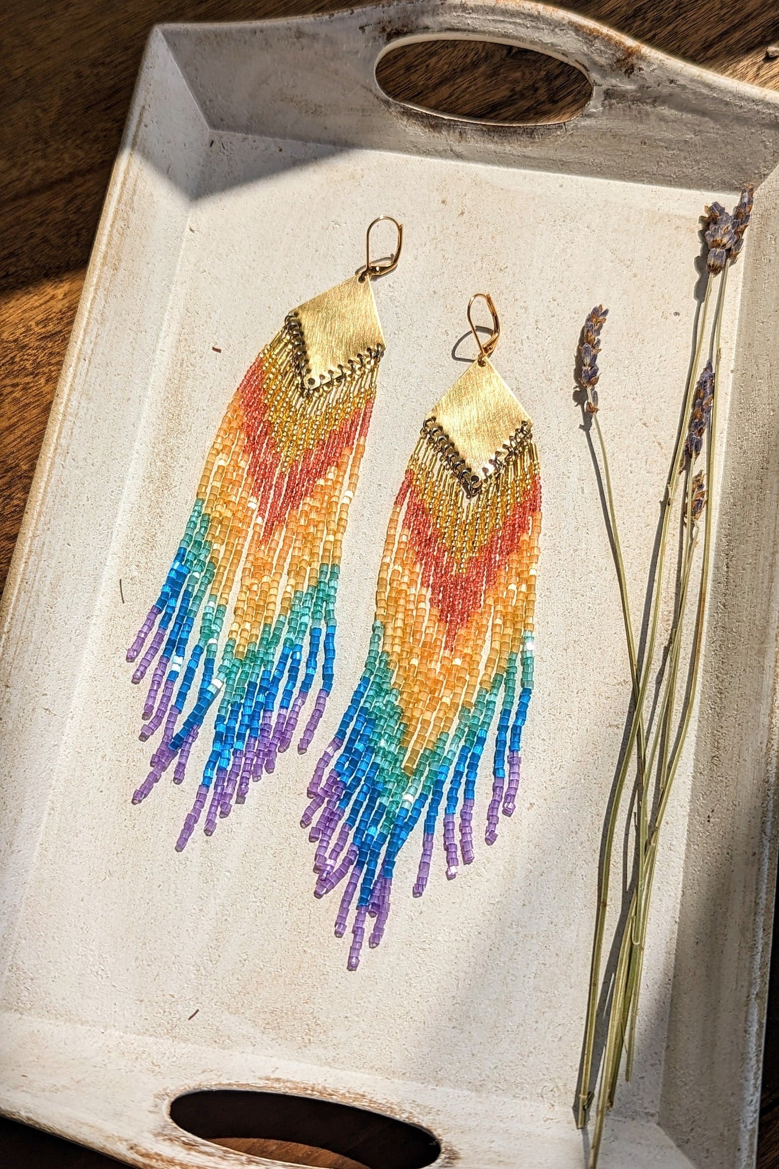 Handcrafted beaded earrings by Moon & Milk featuring vibrant glass beads in rainbow hues with brass accents, showcasing a boho and colorful design.