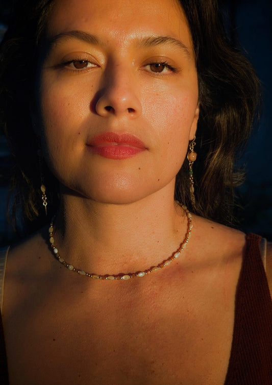 Woman wearing a gemstone necklace with a dark background.