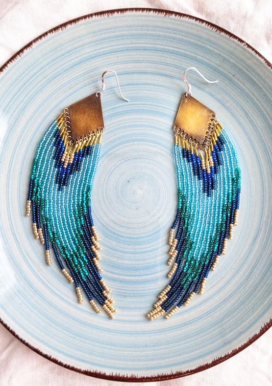 Moon & Milk beaded earrings with flowing fringe in teal, navy, and turquoise, handcrafted with brass to reflect the serene blues of Switzerland’s lakes.