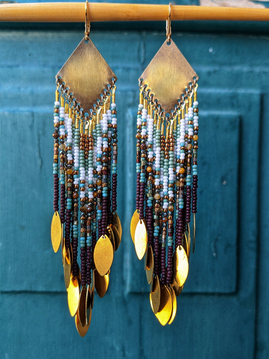 Handcrafted beaded earrings by Moon & Milk with brass diamond tops, seed bead fringe in brown, turquoise, and white, and golden brass disc charms.